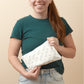 Person holding a white pouch with 'LOLA' branding against a beige background