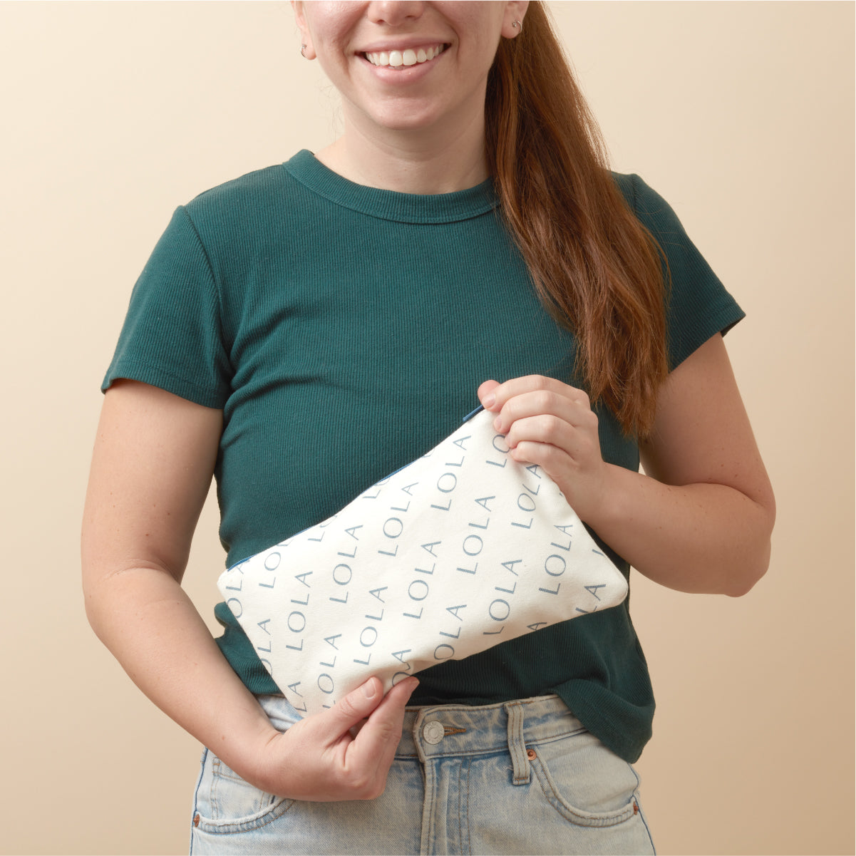 Person holding a white pouch with 'LOLA' branding against a beige background