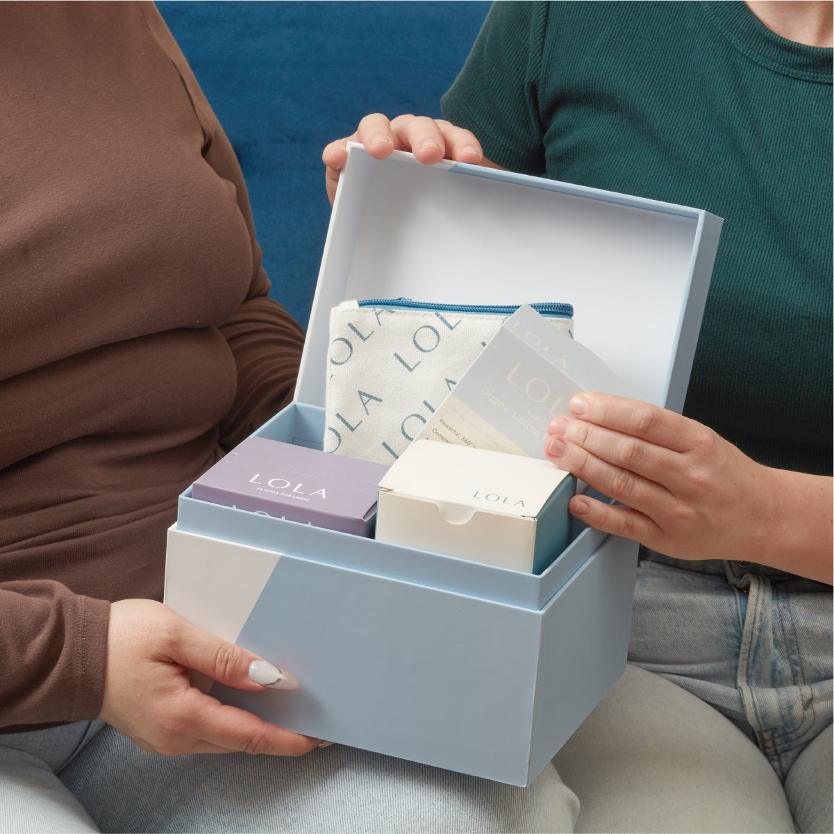 Two people opening a box containing Lola products.