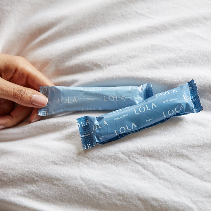 Compact plastic applicator tampons | 2 tampons on a soft fabric background with a women&